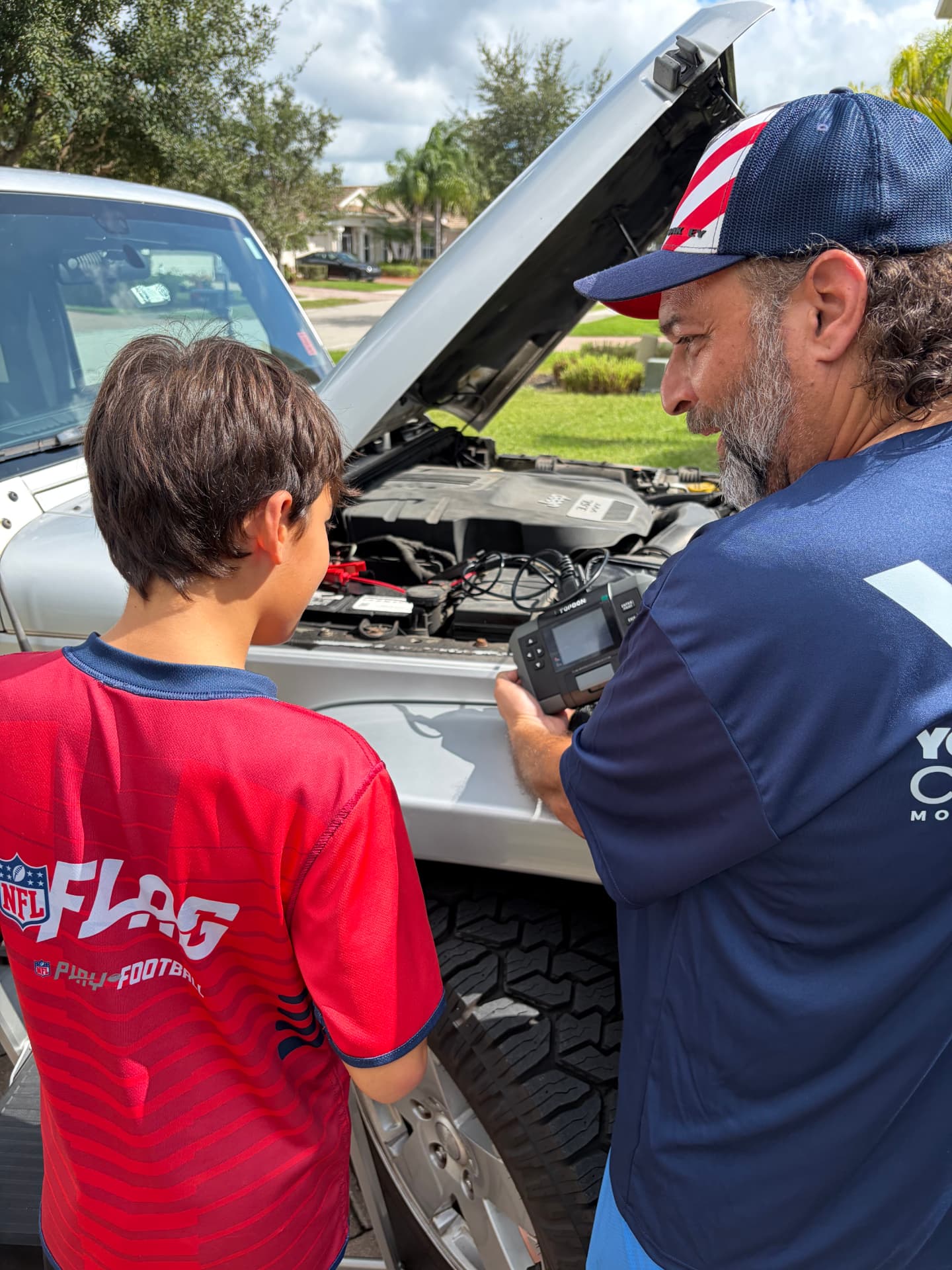 A mechanic showing a boy how to run a car battery test